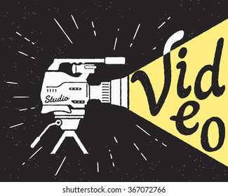 Professional video camera with yellow light and video letters. Retro stylized illustration on black background with grunge texture and sunburst