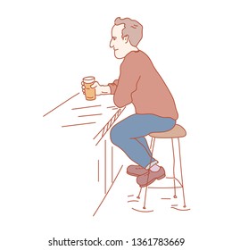 Pub vistor sitting with a pint of beer in his hand