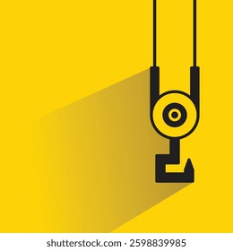 pulley and crane hook icon with shadow yellow background