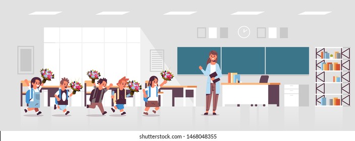 pupils giving flowers to female teacher standing in front of board in classroom education back to school concept modern class room interior flat horizontal full length