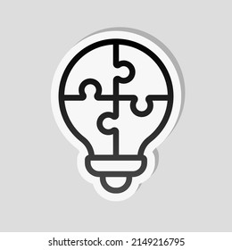 Puzzle lightbulb, team idea, simple icon. Linear sticker, white border and simple shadow on gray background