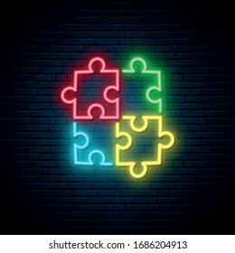 Puzzle neon sign. Bright Autism symbol on dark brick wall background. World Autism Day neon signboard. Vector illustration.