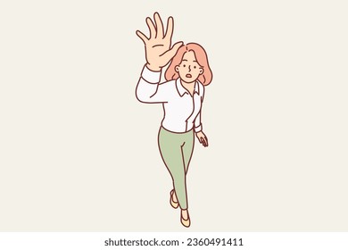 Puzzled woman raises hand up and stretches palm to screen, urging them to stop taking pictures and forbidding them to take new photos. Girl making stop gesture or trying to catch flying insect
