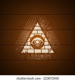 Pyramid with eye on wooden background