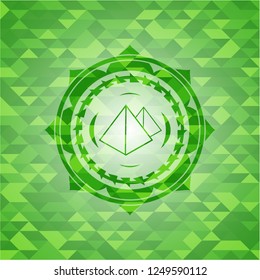 pyramids icon inside green emblem with triangle mosaic background
