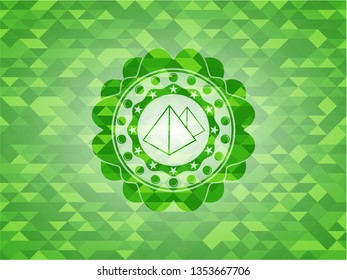 pyramids icon inside green emblem with mosaic background