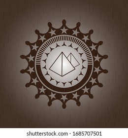 icono de las pirámides dentro de un emblema de madera realista