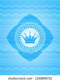queen crown icon inside light blue water wave badge.