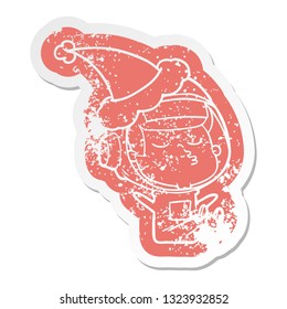 quirky cartoon distressed sticker of a confident astronaut wearing santa hat