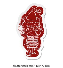 quirky cartoon distressed sticker of a curious boy with lots of books wearing santa hat
