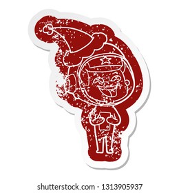 quirky cartoon distressed sticker of a laughing astronaut wearing santa hat