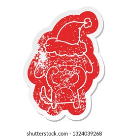 quirky cartoon distressed sticker of a tired dog wearing santa hat