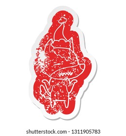 quirky cartoon distressed sticker of a wolf showing teeth wearing santa hat
