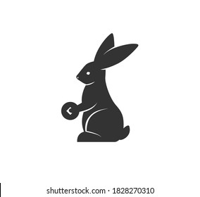 Rabbit silhouette holding coin vector illustration. Black and white bunny logo. Isolated on white background.