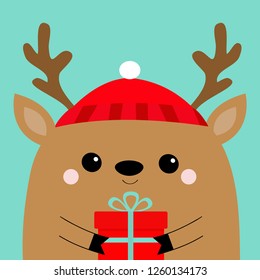 Raindeer deer head face holding gift box. Red hat, nose, horns. Merry Christmas. Happy New Year. Cute cartoon kawaii baby character. Funny animal. Flat design. Hello winter. Blue background. Vector