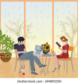 Rainy day. A young couple sitting and enjoying the living room. Girl  reading a book. The young man looks at a laptop