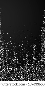 Random white dots Christmas background. Subtle flying snow flakes and stars on black background. Alluring winter silver snowflake overlay template. Ideal vertical illustration.