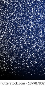 Random white dots Christmas background. Subtle flying snow flakes and stars on dark blue background. Amusing winter silver snowflake overlay template. Shapely vertical illustration.