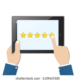 Ranking on tablet. Hands holding black tablet with yellow rank stars on screen. Man chooses stars for review and rating. Concept of voting and evaluation.