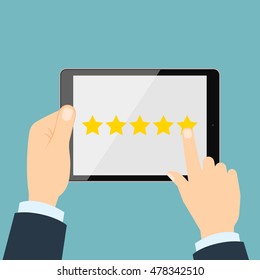 Ranking on tablet. Hands holding black tablet with yellow rank stars on screen. Man chooses stars for review and rating. Concept of voting and evaluation.