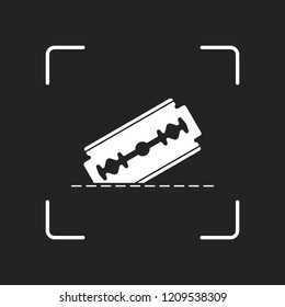 razor blade and cutting line. simple icon. White object in camera autofocus on dark background