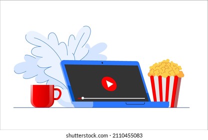 Ready to watch a movie online on a streaming platform. A laptop with a red play button on the screen stands on a table near popcorn, teacup, and potted plant.