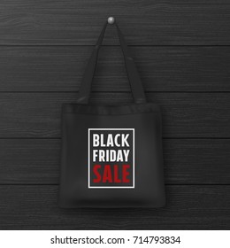 Realistic black textile tote bag with the inscription BLACK FRIDAY SALE. Closeup on wood black wall background. Design template for advertising, branding, mockup. Stock vector. EPS10.