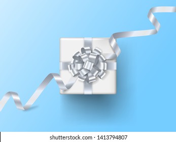 Realistic gift box with silver bow and ribbons isolated on blue background. Vector illustration. Top view.