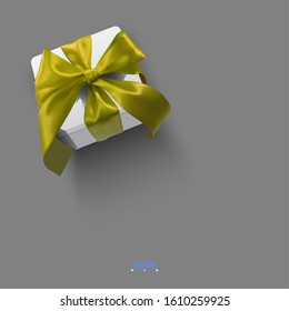 Realistic vector illustration of a gift box with a gold ribbon and a bow on a gray background. 3D white box tied with gold festive ribbon.