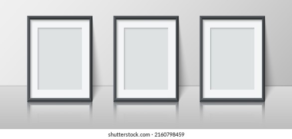 Realistic vertical blank picture frame set stands near the wall on the shelf. Three empty photo frame mockup with reflection for pictures, photograph, poster. Decorative design element interior