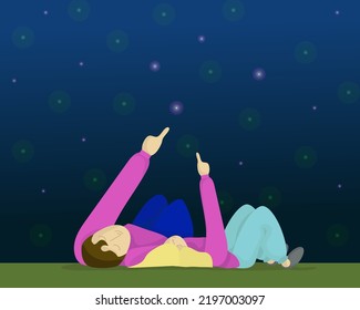 Rear View Of A Couple In Love Lying Outdoors Under The Stars On A Romantic Evening Together. A Man And A Woman Look At The Dark Night Sky, Enjoy The Romance On A Date. Love And Relationship Concept.