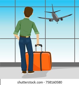 Rear view of man standing with a suitcase in airport watching landing aircraft