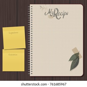 Recipe notebook with hand drawn text. Olive and laurel leaves with adhesive tape. Yellow sticky notes. Blank space.