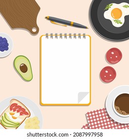 Recipes book. Notepad and pencil for writing recipes surrounded by vegetables, coffee, eggs and a cutting board.