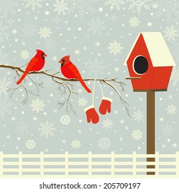 Red birds on branch with snow and birdhouse
