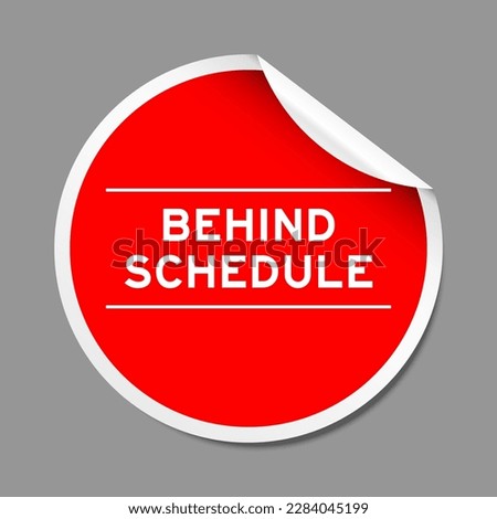 Red color peel sticker label with word behind schedule on gray background