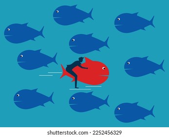 The red fish swims in the opposite direction from the other fish. Courage and confidence. business difference