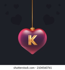 Red glass heart toy with a golden 3D letter K inside. Valentine day decoration.Design element for banner, invintation or any advertising