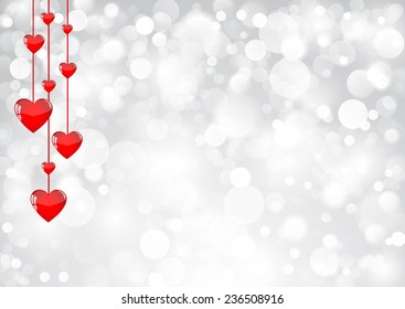 Red hearts hanging on a silver shimmering background