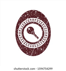 Red key icon inside rubber seal with grunge texture