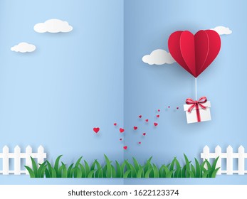 Red origami hot air balloon in heart shape with gift box flying on the sky over the green meadow in Valentine's day with mini hearts on blue background. Vector art design in paper cut pop up style. 