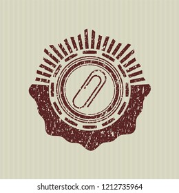 Red paper clip icon inside distressed grunge stamp