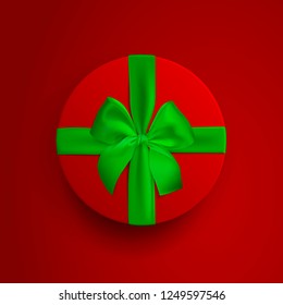 Red round box with green ribbon and bow isolated on red background. Box cover top view. Template for your presentation design, banner, brochure or poster. Vector illustration.