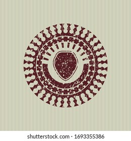 Red shield icon inside rubber seal with grunge texture