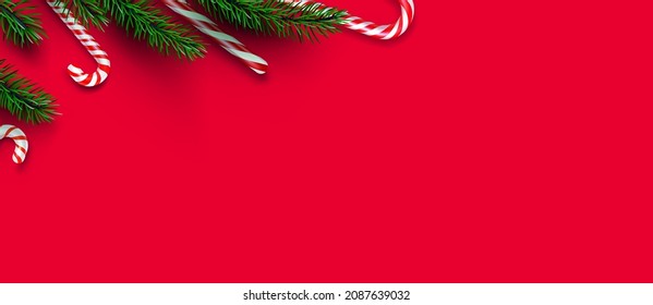 Red and white striped candy cane sticks with fir branches border. Red background. Space for text. Vector illustration.
