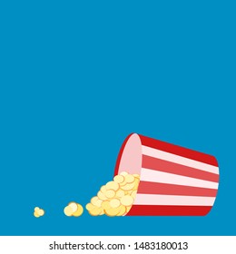 Red white striped container box lying tipped over with popcorn spread out. Pop corn bucket lying on its side with grains spilling out of it. Movie snack. Popcorn time. Watch and eat. Blue background.