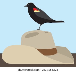 A red winged blackbird is resting peacefully on a cowboy hat on the ground