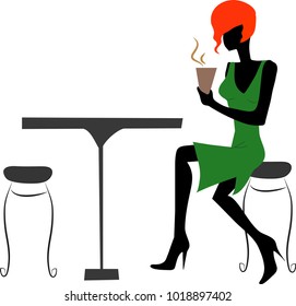 Red-haired girl sitting at the table in a green dress and drinks coffee