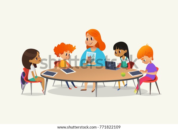 授業中にテーブルの周りに座っている子どもたちに写真を見せる赤毛の女性の先生 ノートパソコンとタブレットpcを使う 小学校の授業 でガジェットを使う子どもたち カラフルなベクターイラスト のベクター画像素材 ロイヤリティフリー