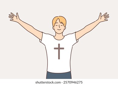 Religious man feels free and empowered by faith, dressed in t-shirt with crucifix on chest. Religious guy smiles, rejoicing in involvement in christian faith and absence of sins that destroy soul